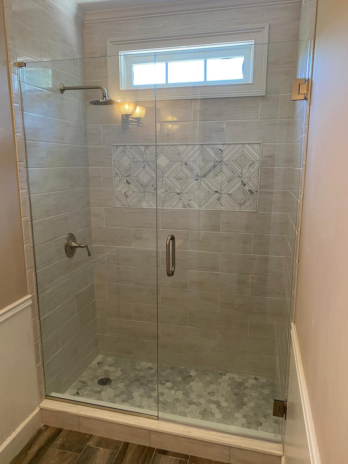 Shower with geometric tile pattern and window above