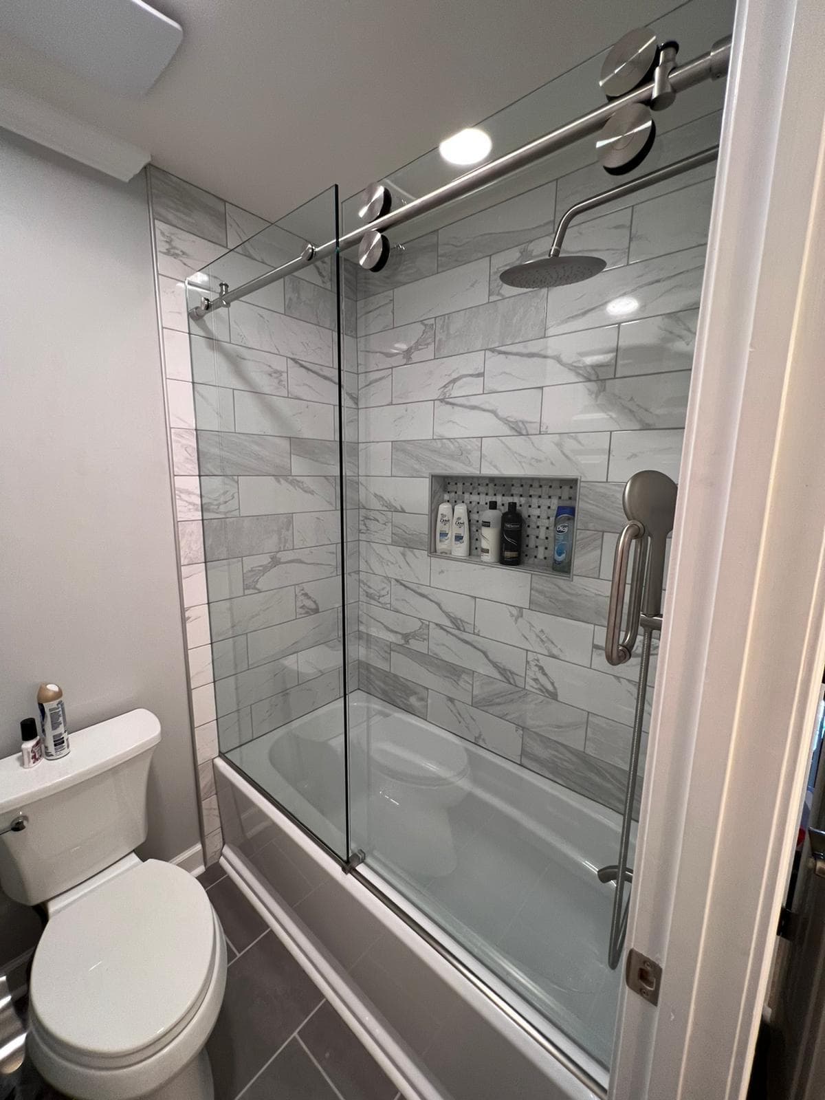 Tub-shower combo with sliding glass doors and marble-style tile