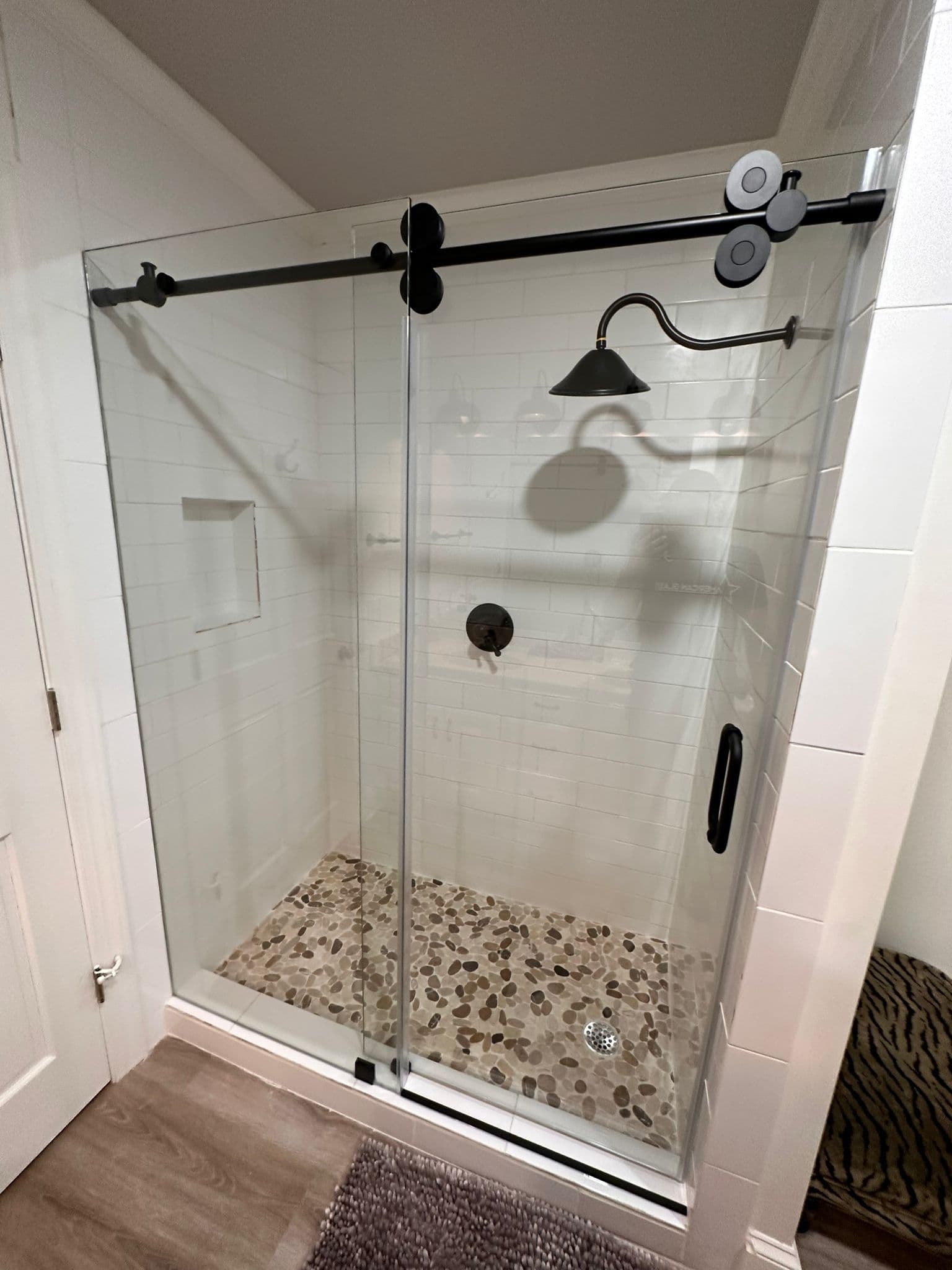 Shower with pebble tile floor and dark fixtures