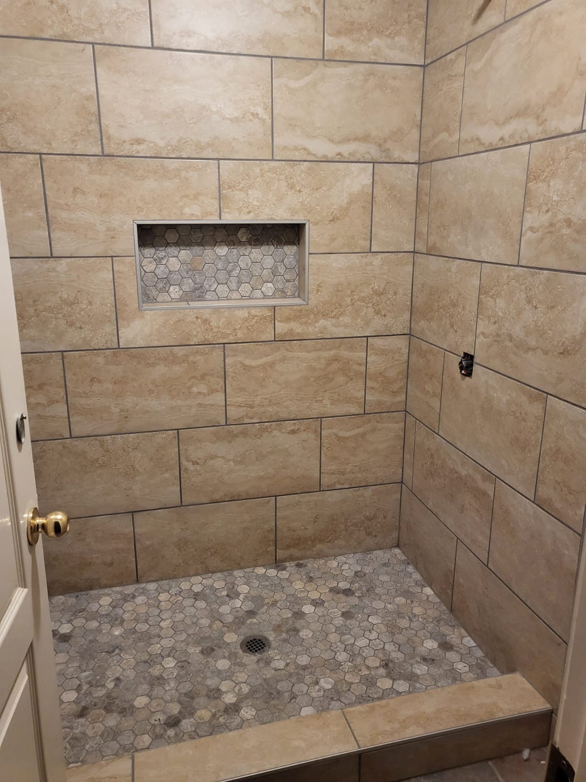 Shower with beige tile walls and hexagon tile floor