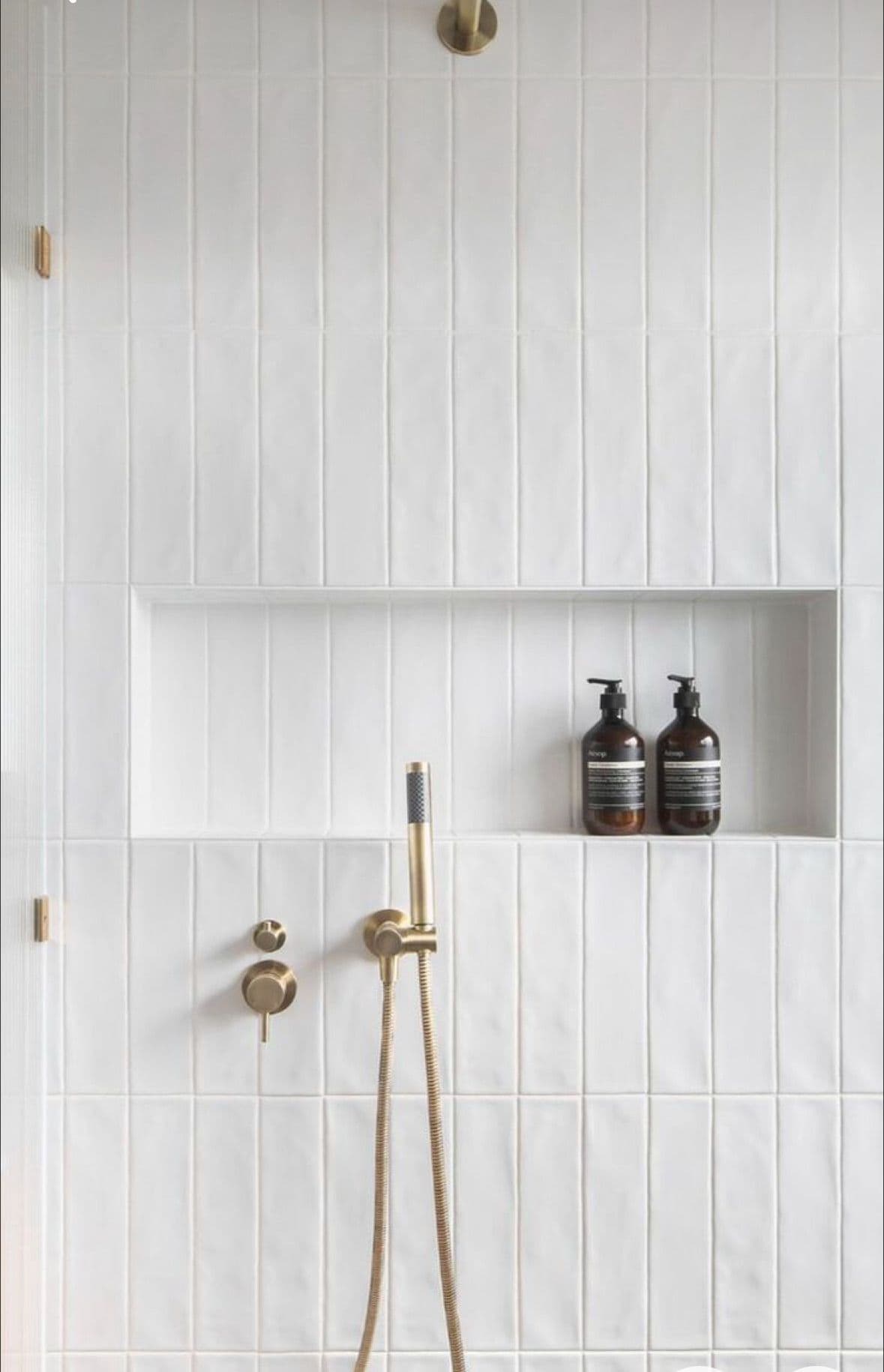 Minimalist shower with vertical white tiles and built-in shelf