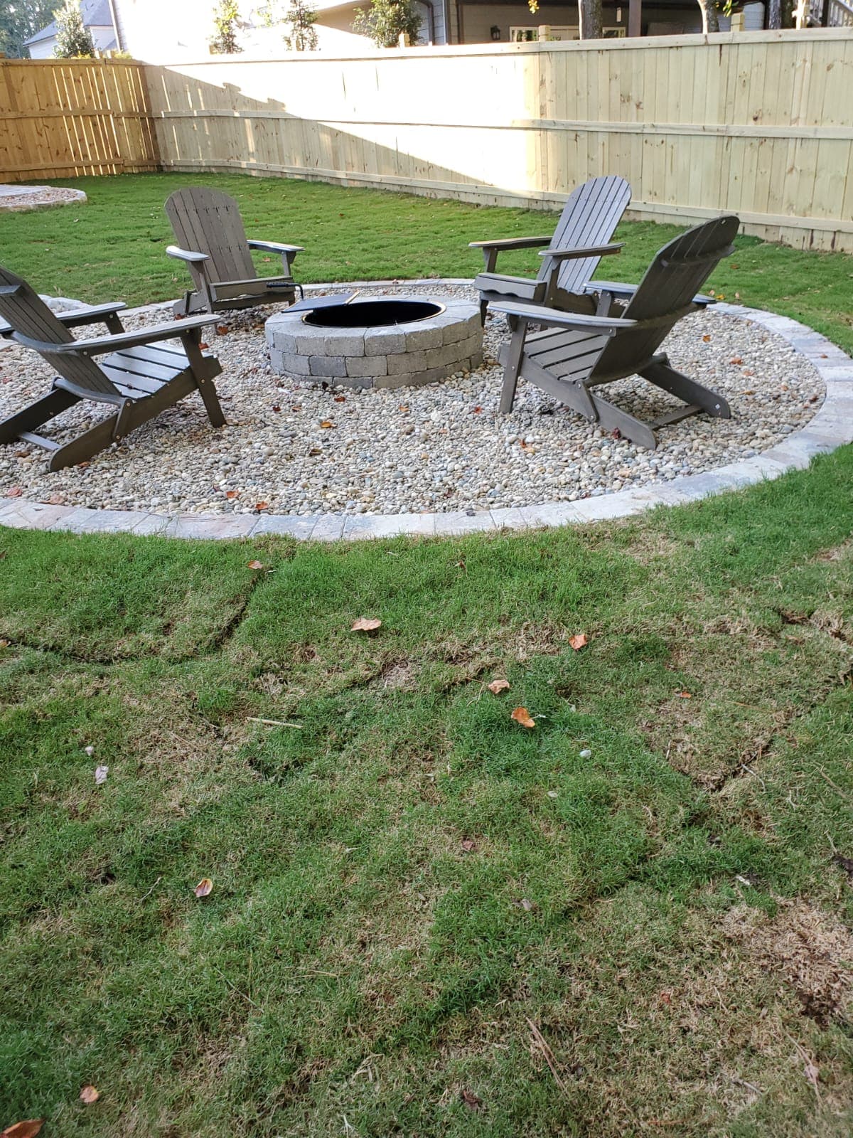 Circular fire pit area with gravel and Adirondack chairs