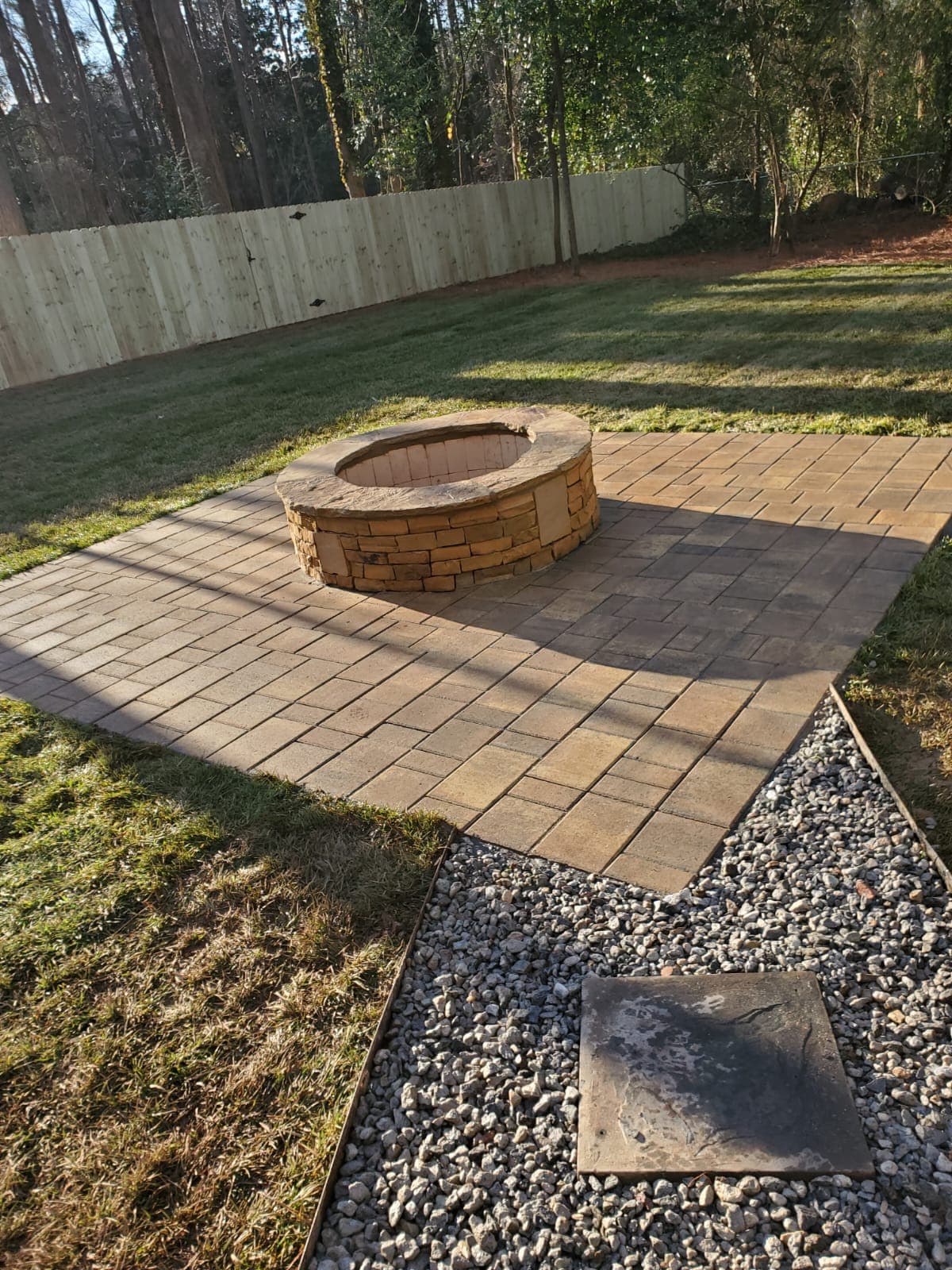 Paver patio with stacked stone fire pit and gravel walkway