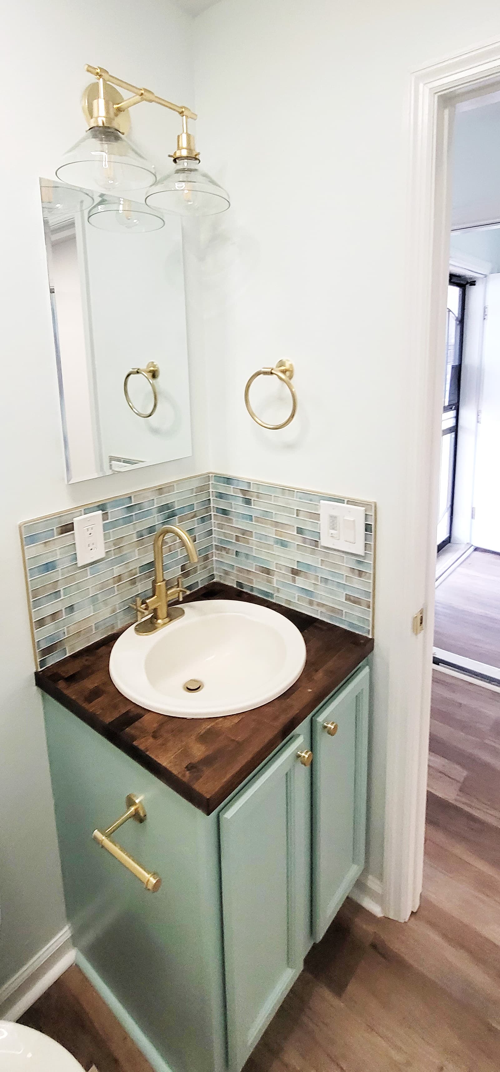Compact vanity with backsplash and brass fixtures