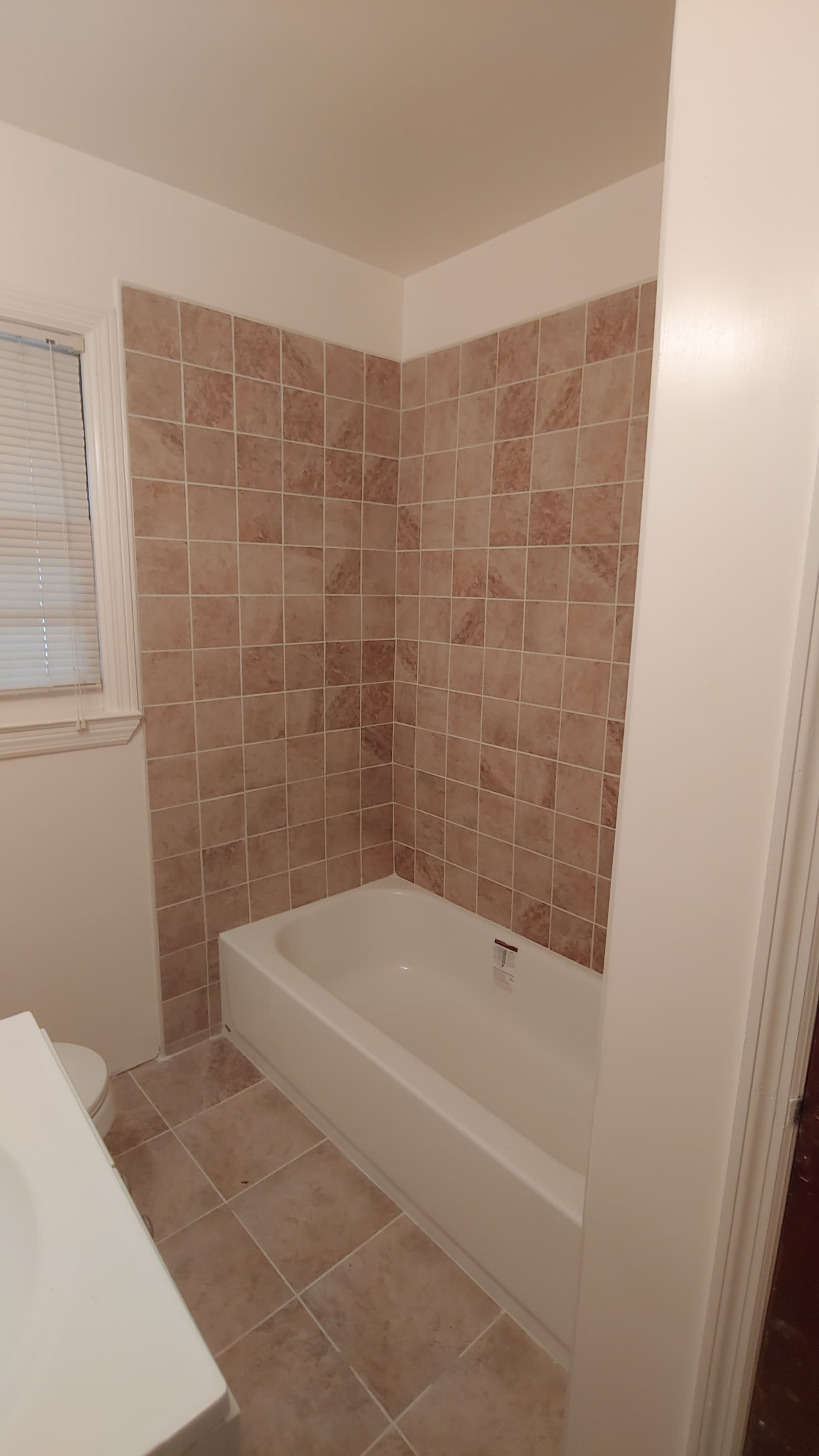 Remodeled bathroom with tub and tiled shower wall